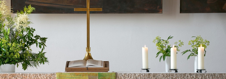 Altar mit Kreuz, Blumen und Kerzen